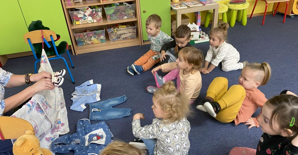 nauczycielka pokazuje dzieciom buciki z zapytaniem na jaką część ciała ma założyć misiowi