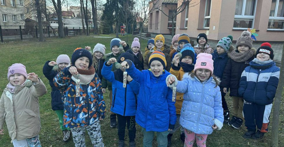 Wszystkie dzieci z grupy pozują do wspólnego zdjęcia prezentując smakołyki dla ptaków.