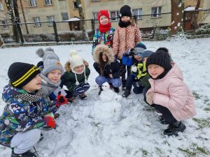 Dzieci z grupy V pozują do zdjęcia z ulepionym przez siebie bałwankiem.