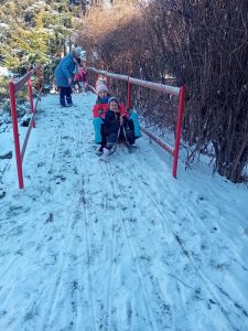 Dziewczynka siedzi na sankach z panią.